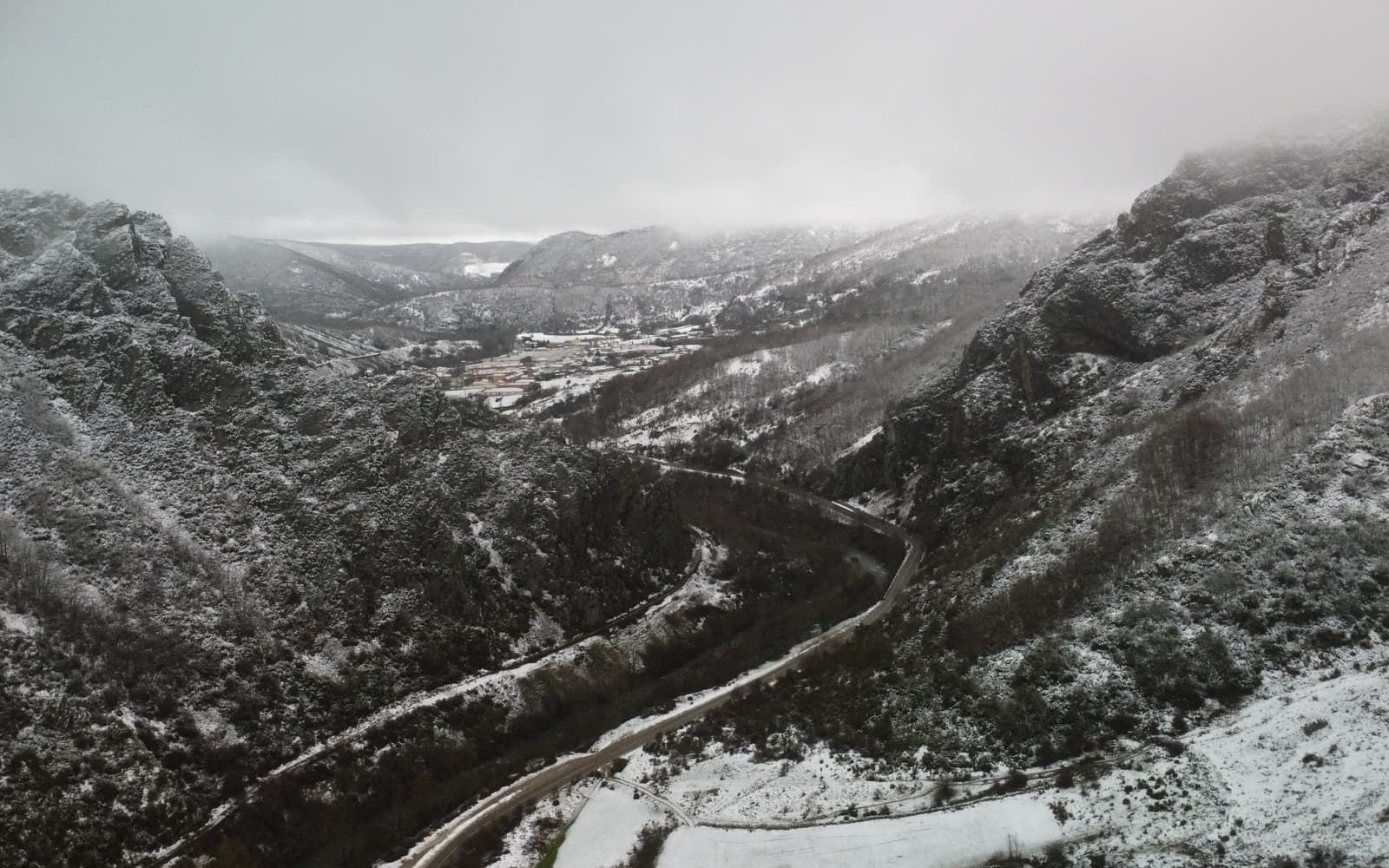 Valle de montaña nevado entre la niebla, León